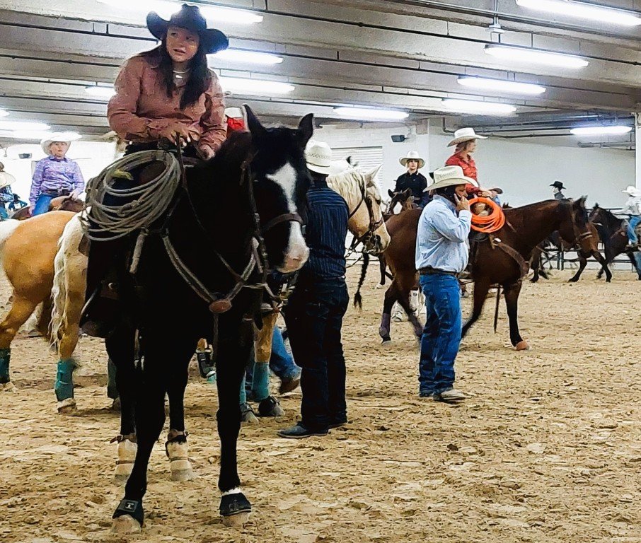 Pre-rodeo warmup arena, female contestant peeks out of Priefert Pavilion as seen at: rodeo Priefert Pavilion; rodeo South Point Arena; rodeo South Point; and rodeo Horseman’s Park.