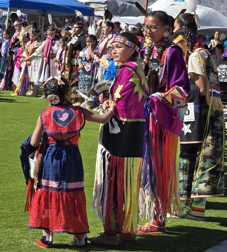 Grand Entry as a group of women laugh preparing to perform as seen in Powwows: Cedar; Cedar City; Duck Valley; Elko; Ely; Fallon; Fort Mojave; Goshute; Moapa; Muckleshoot; Nevada Day; Numaga; Red Dress; Sacred Visions; Stewart; Sycuan; UNLV;  UNR; Univ. of Nev. Reno; and Walker River.