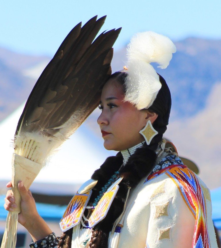 Snow Mountain Paiute Pow Wow Grand Entry as a young woman uses her eagle feather fan to protect herself from the sun as seen in Powwows: Duck Valley; Elko; Ely; Fallon; Fort Mojave; Goshute; Moapa; Muckleshoot; Nevada Day; Numaga; Red Dress; Sacred Visions; Stewart; Sycuan; UNLV; Univ. of Nev. Reno; and Walker River.