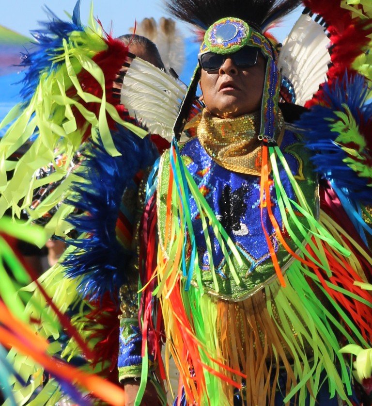 Snow Mountain Paiute Pow Wow Grand Entry as older man in sunglasses with spectacular costume responds to the drums as seen in Powwows: Cedar; Cedar City; Duck Valley; Elko; Ely; Fallon; Fort Mojave; Goshute; Moapa; Muckleshoot; Nevada Day; Numaga; Red Dress; Sacred Visions; Stewart; Sycuan; UNLV;  UNR; Univ. of Nev. Reno; and Walker River; Western Navajo Fair.