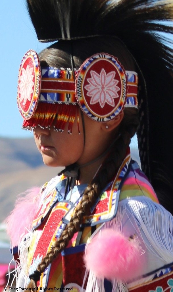 Closeup of a Native American female hidden by her headdress in the Grand Entry as seen in powwows: Lakota; Mohave; Mojave; Mohawk; Mohegan; Muscogee; Muscogee Nation; Nakota; Navajo; and Navajo Nation.