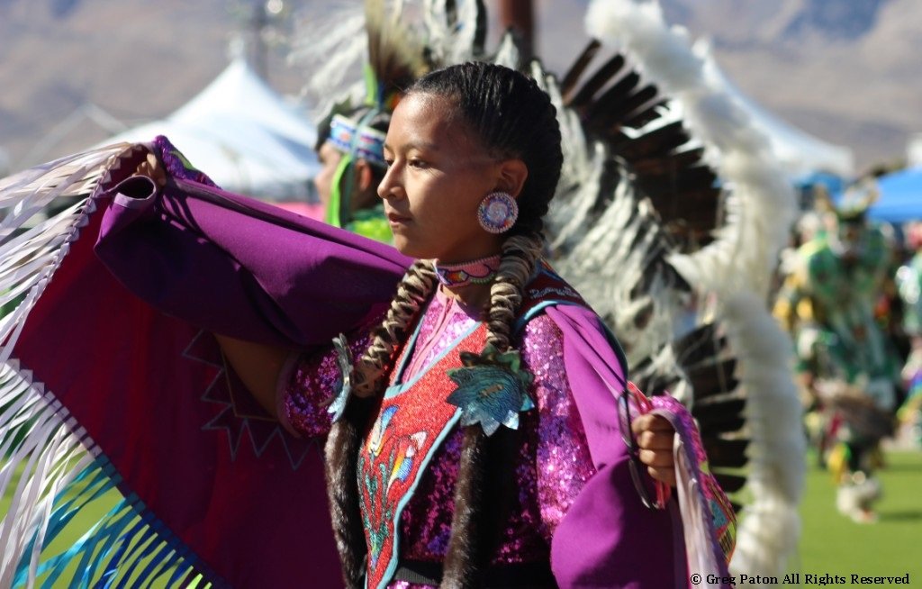 Young Native American female in a stunning violet costume in the Grand Entry as seen in powwows: Lakota; Mohave; Mojave; Mohawk; Mohegan; Muscogee; Muscogee Nation; Nakota; Navajo; and Navajo Nation.