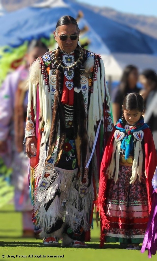 Father and daughter walk in Grand Entry as seen in powwows: Apache; Apache Nation; Arapaho; Blackfeet; Blackfeet Nation; Blackfoot; Black Hills; Cherokee; Cherokee Nation; and Cheyenne.
